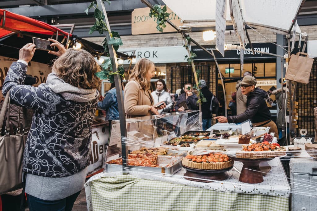 Woman buying cakes from a market stall at Greenwich Market, London's only market set within a World Heritage Site.