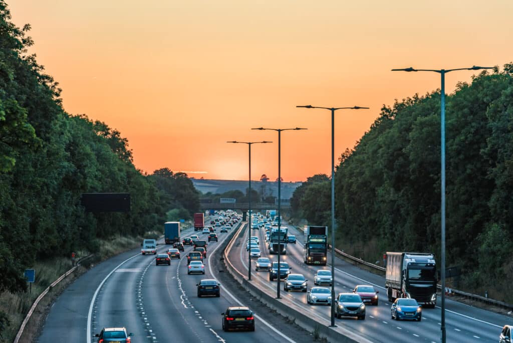 Sunset view of busy UK motorway traffic in England.